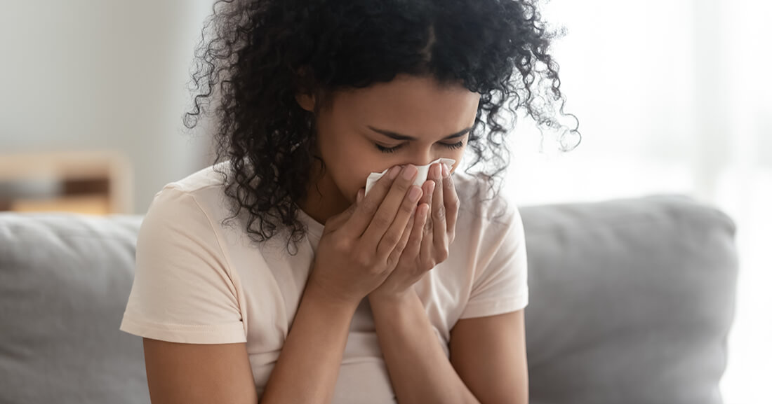 residential cleaning services image of woman sneezing into napkin in home freshly cleaned